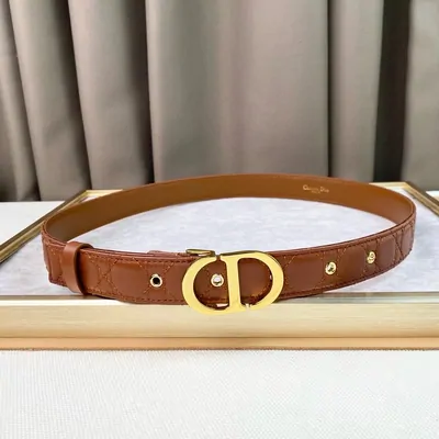 Tan leather belt coiled on a stand, with a gold interlocking buckle