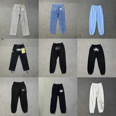 Nine pairs of trousers laid flat, blue and grey jeans across the top row