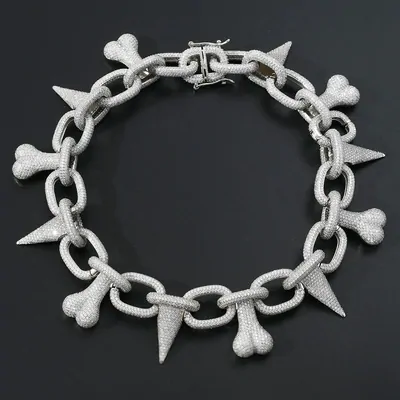 Pave-set chain necklace with bone and spike pendants on a dark ground