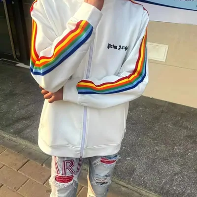 White track jacket with rainbow shoulder stripes, worn open over jeans