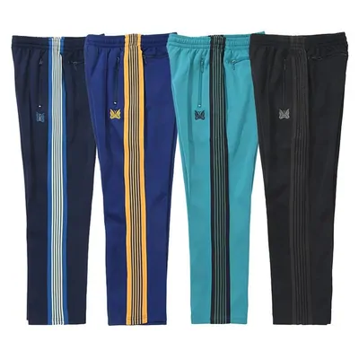 Four striped track pants in navy, blue, teal and black, laid side by side