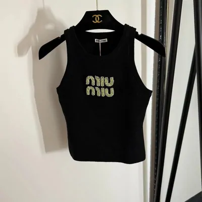 Black knitted tank top with a beaded logo, on a velvet hanger
